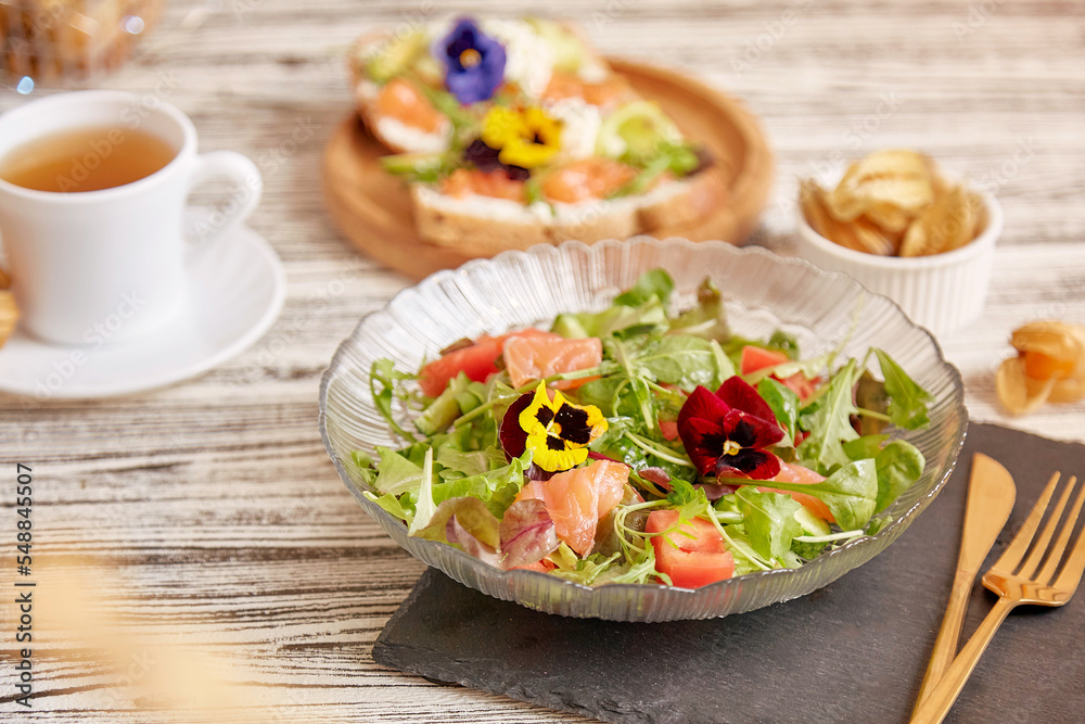 Healthy Mediterranean pescetarian salad with smoked salmon, vegetables, greens and edible flowers. Tea with appetizers. Healthy dinner.