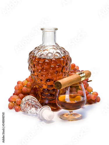 Open decanter and glass filled with cognac, cigar and bunch of grapes