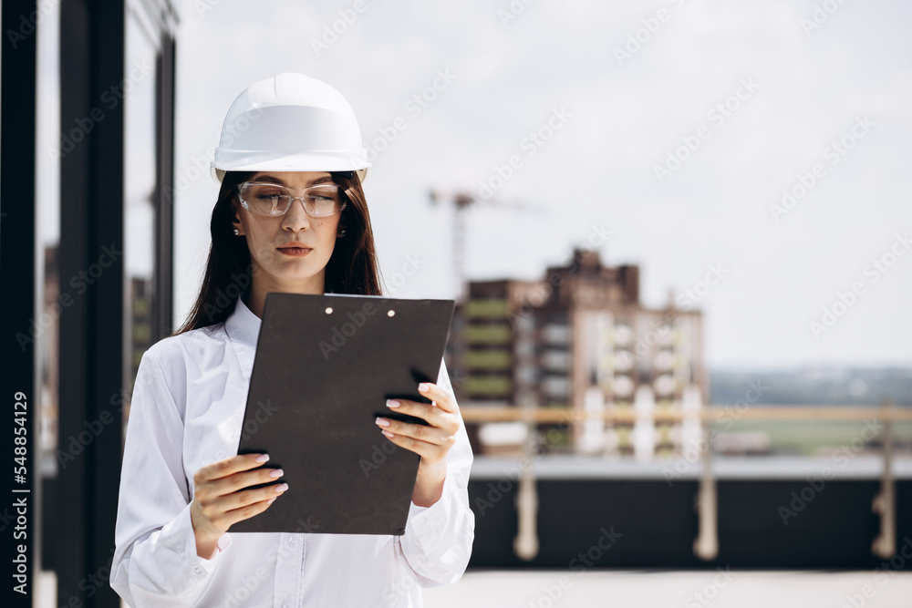 Business woman in white helmet standing on the roof building Business woman in white helmet standing on the roof building