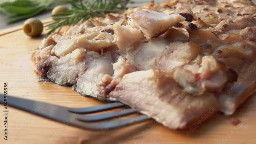 Close-up of fork taking piece of grilled Mackerel fish fillet from wooden board Close-up of fork taking piece of grilled Mackerel fish fillet from wooden board