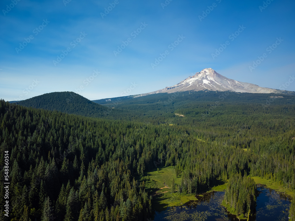 High mountain covered with snow under blue sky and green rolling hills. Small lake. The beauty and grandeur of pristine nature, environmental protection. High mountain covered with snow under blue sky and green rolling hills. Small lake. The beauty and grandeur of pristine nature, environmental protection.