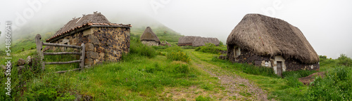 Vistas panorámicas de casas típicas de la Braña de Pornacal, en Asturias, con techo de paja, en verano, un día de niebla blanca y césped verde, España, 2021