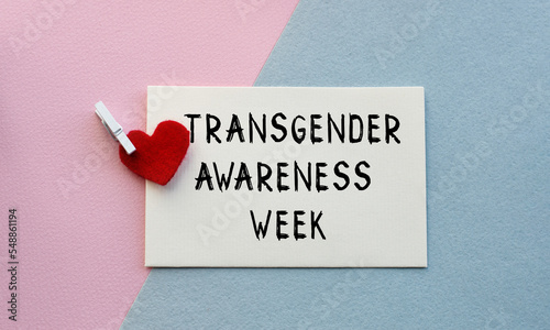 An open envelope with the text TRANSGENDER AWARENESS WEEK, on a pink and blue background with a decor of felt hearts and a flower. Flat lay, top view. LGBT concept.