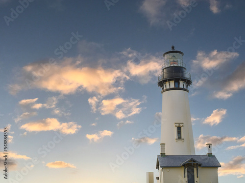 A tall white lighthouse against a dark blue sky with pink clouds. Twilight. Beauty of nature  historical site  romance  travel  relaxation  solitude  romance.