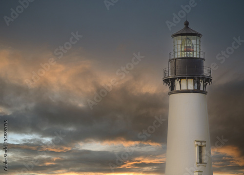 Beautiful white lighthouse against the sky with thunderclouds. Twilight. Beautiful landscape. Maritime navigation, architecture, construction, travel, tourism, weather, ecology.