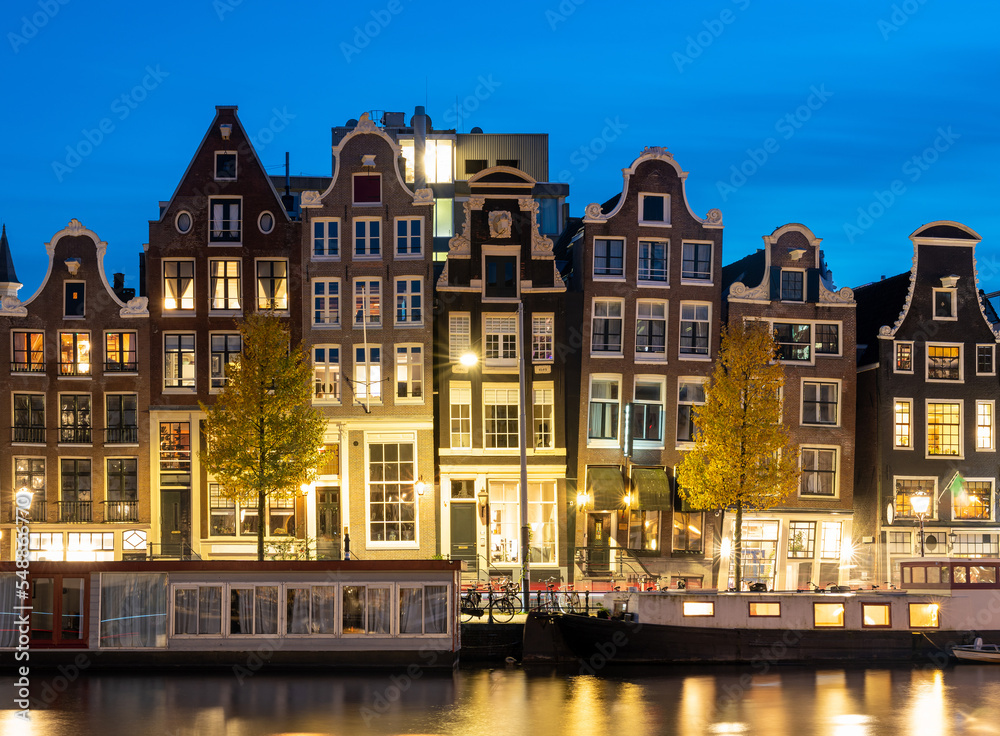 Amsterdam in the evening, typical dutch houses and houseboats along the river Amstel