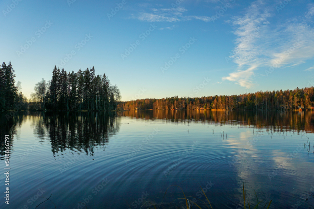The clouds are reflected on the surface of the lake and the sunlight is reflected on the horizon