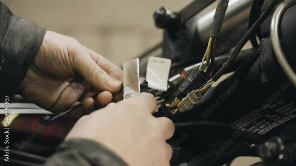 A mechanic cleans electrical wires from insulation to repair electrical equipment in a motorcycle. Close-up. Transport concept A mechanic cleans electrical wires from insulation to repair electrical equipment in a motorcycle. Close-up. Transport concept