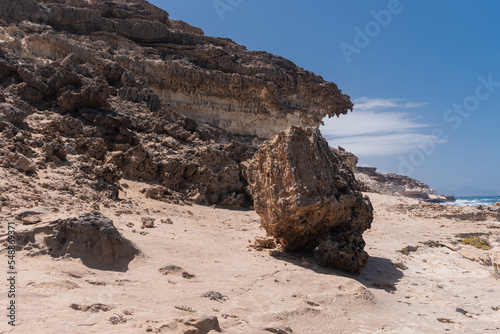 Hiking trail alongside wild Atlantic ocean and steep white to light red desert cliffs and sands, Fuerteventura 