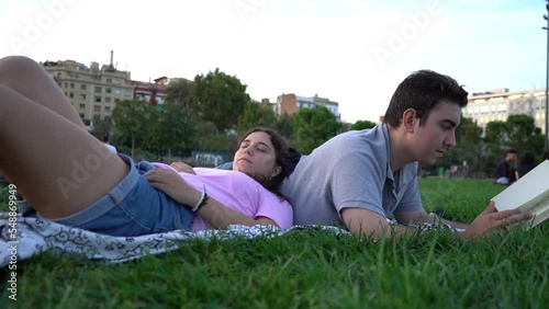 young caucasian woman and man student friends relaxing, having fun, reading and studying in the park