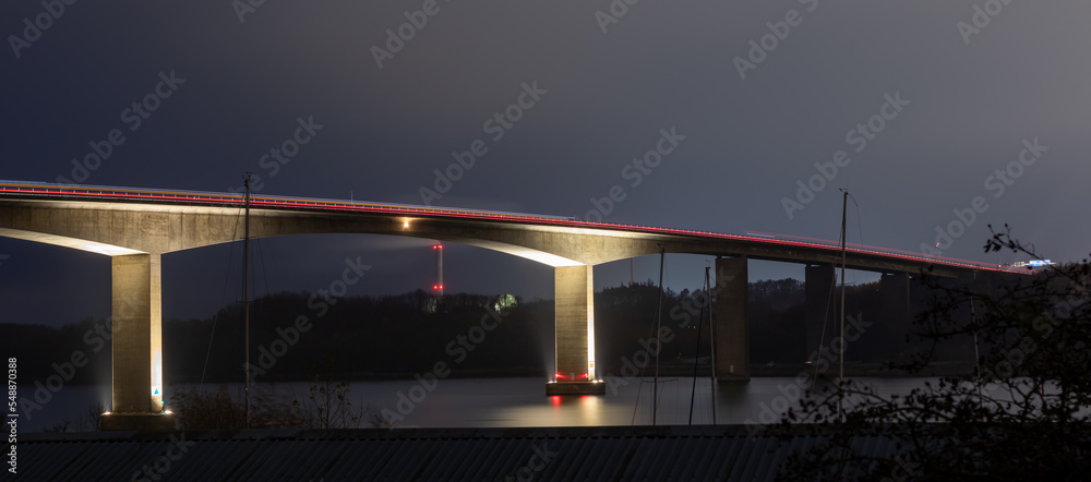 Landscape view of traffic on the illuminated highway Alssundbroen, high car bridge over Alssund north of Sønderborg, Denmark. Long-exposure shot at night.