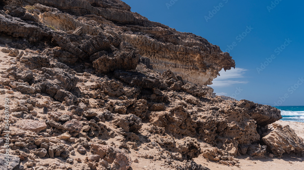 Steep cliff and rocky desert coastline, hiking trail alongside wild Atlantic Ocean, Fuerteventura, Spain