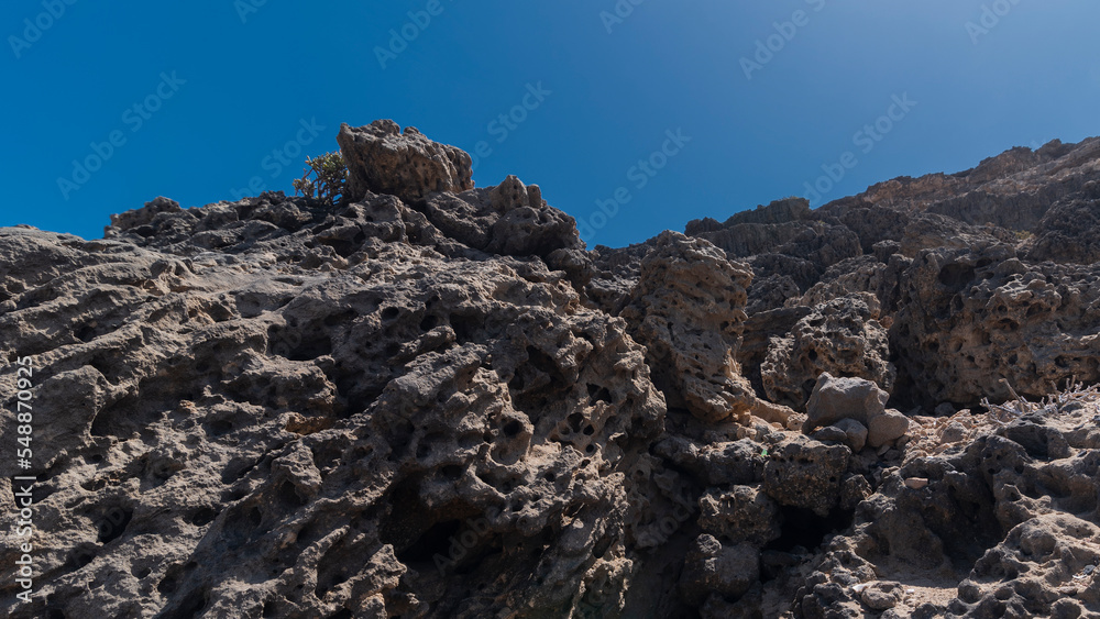 Dry dark desert full or rocks with holes during hot sunny day, Canary Islands