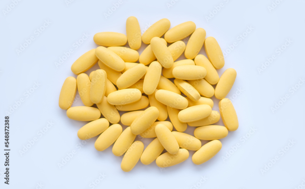Close-up texture of yellow multivitamin tablets on white background. Healthy lifestyle concept Close-up texture of yellow multivitamin tablets on white background. Healthy lifestyle concept