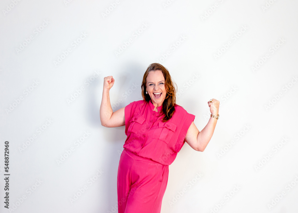 Happy mature woman celebrating her success, with white wall in background. Success and motivation. Happy mature woman celebrating her success, with white wall in background. Success and motivation.