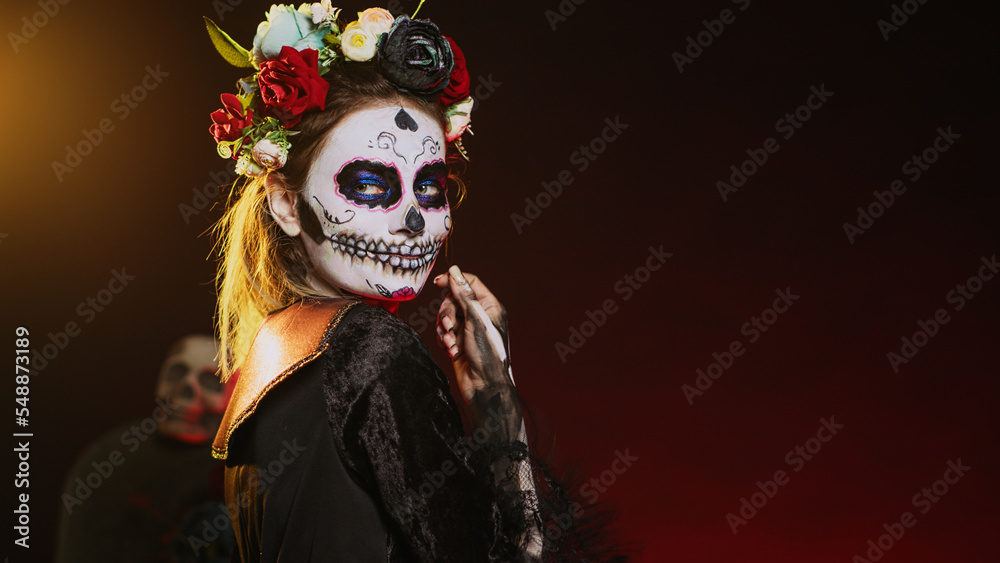 Cavalera catrina luring victims and reaching with hand, tempting and looking flirty on mexican halloween. Lady of death acting horror with skull make up and goddess costume. Handheld shot. Cavalera catrina luring victims and reaching with hand, tempting and looking flirty on mexican halloween. Lady of death acting horror with skull make up and goddess costume. Handheld shot.