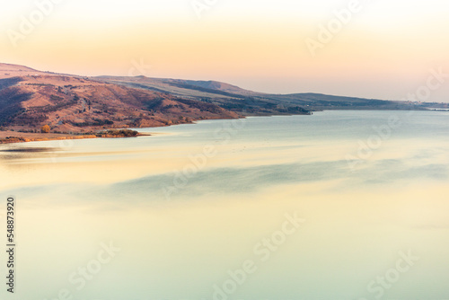 picturesque landscape of the hilly shore of a large lake at sunset © Sergey
