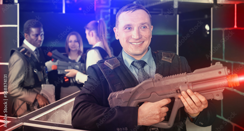 Adult man and his colleagues on background having corporative entertainment in laser tag room