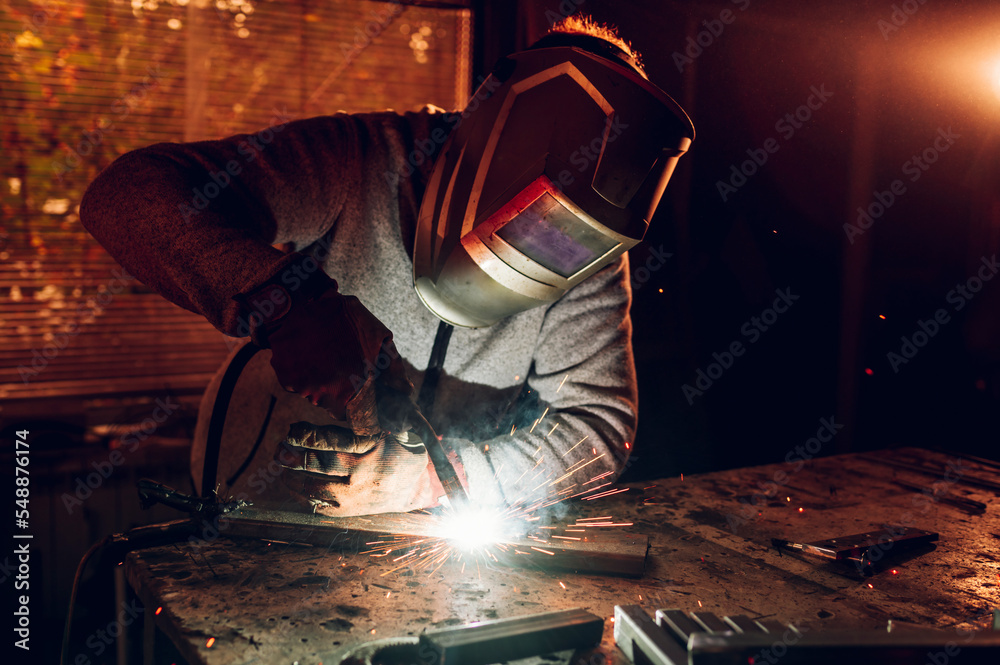 Man worker welding metal with welding machine in a factory or workshop Man worker welding metal with welding machine in a factory or workshop