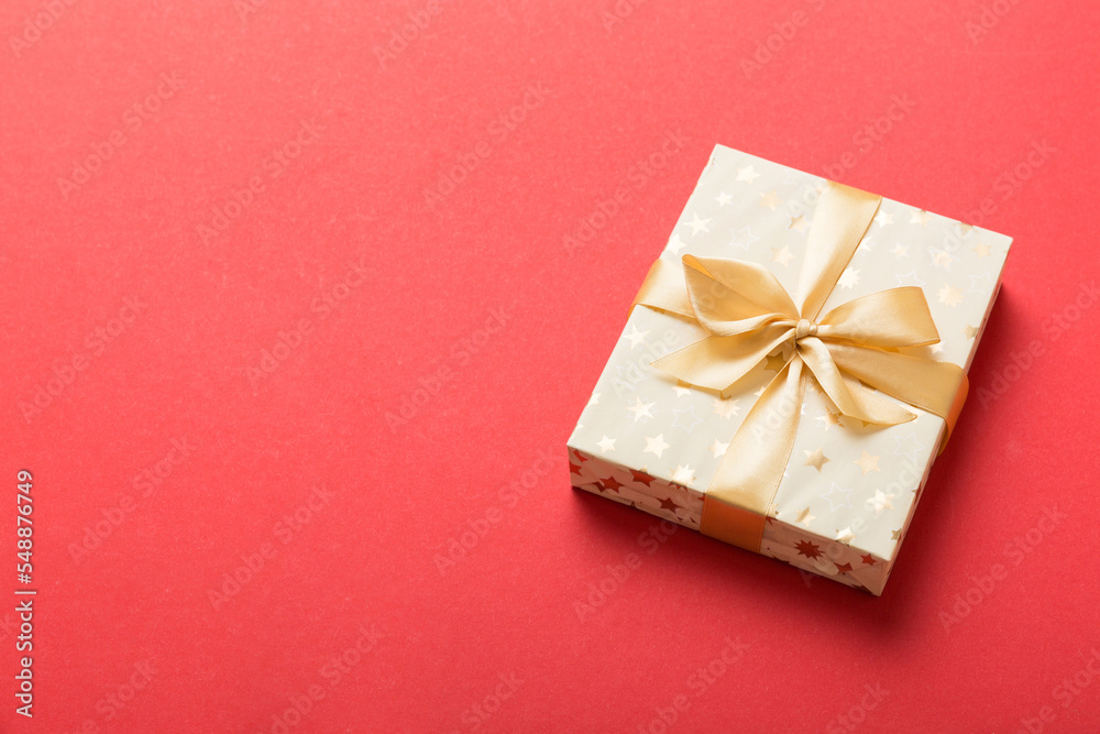 wrapped Christmas or other holiday handmade present in white paper with gold ribbon on colored background. Present box, decoration of gift on colored table, top view with copy space wrapped Christmas or other holiday handmade present in white paper with gold ribbon on colored background. Present box, decoration of gift on colored table, top view with copy space