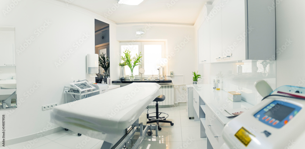 White and comfortable SPA bed standing in the middle of professional, clean and hygienic room for facial and body treatments. Wide copy space shot. High quality photo