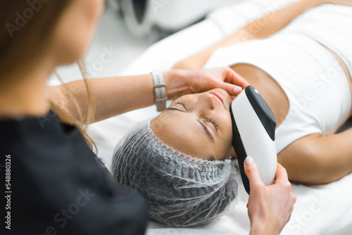 Erbium-yag fractional laser used on young adult Latin woman who is lying down on SPA bed. Cosmetician s POV. Unrecognizable beautician in the foreground. High quality photo