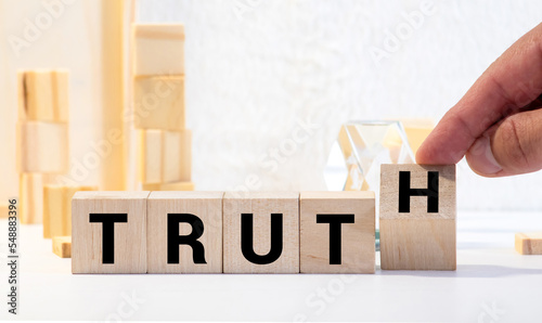 Konstfotografi Hand turned wood cube and changes the word Trust to Truth.