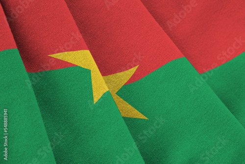 Burkina Faso flag with big folds waving close up under the studio light indoors. The official symbols and colors in banner photo