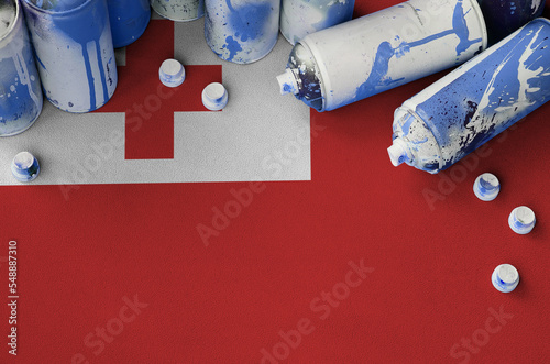 Tonga flag and few used aerosol spray cans for graffiti painting. Street art culture concept photo