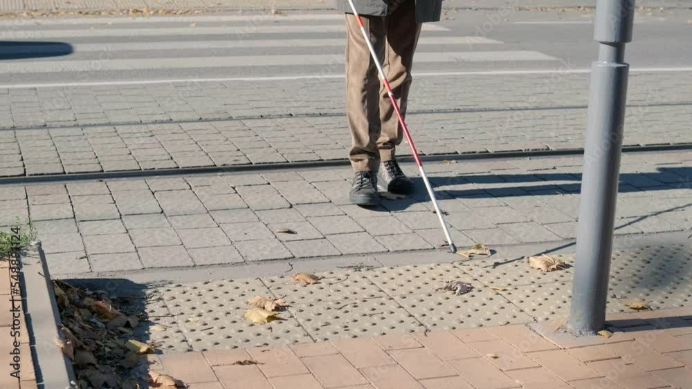 Visually impaired man crossing the road with his stick with the help of ...