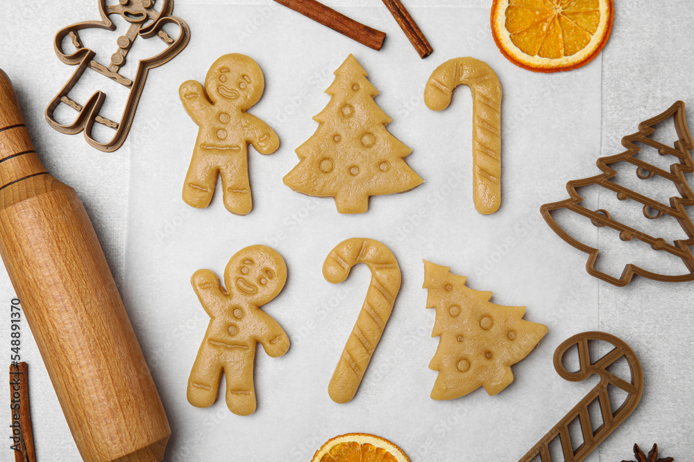 Christmas treat. Flat lay composition with cookie cutters and dough on light table Christmas treat. Flat lay composition with cookie cutters and dough on light table