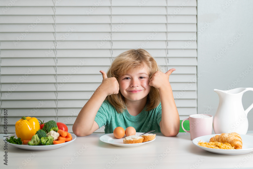 Funny blonde little boy having breakfast. Milk, vegetables and fruits healthy food nutrition for children. Funny blonde little boy having breakfast. Milk, vegetables and fruits healthy food nutrition for children.