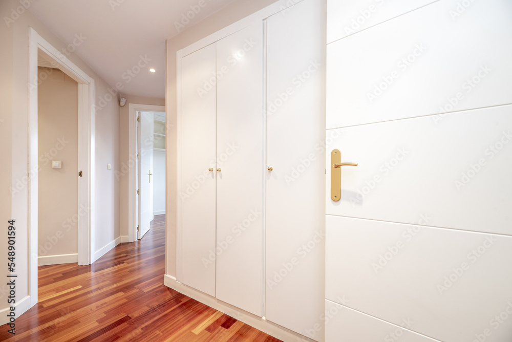 Distributor corridor of a house with white carpentry and built-in wardrobes of the same material Distributor corridor of a house with white carpentry and built-in wardrobes of the same material