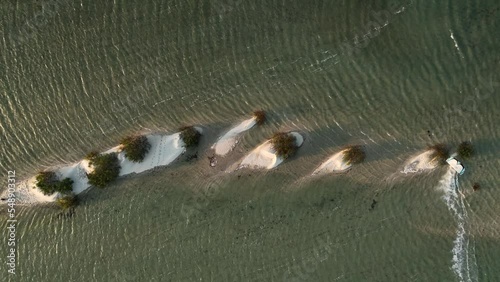 Aerial top down shot of professional kiteboarder surfing and Jumping over sandy island at sunset - Tatajuba,Brazil
