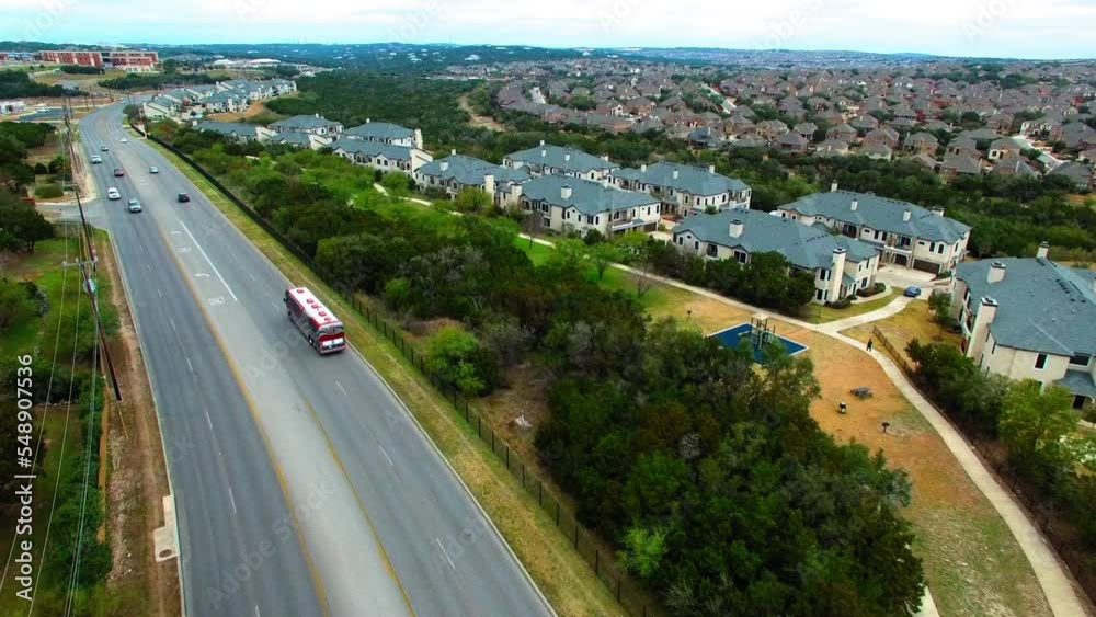 Aerial Forward Shot Of Modern Tour Bus Moving On Road By Roofed Houses - San Antonio, Texas Aerial Forward Shot Of Modern Tour Bus Moving On Road By Roofed Houses - San Antonio, Texas