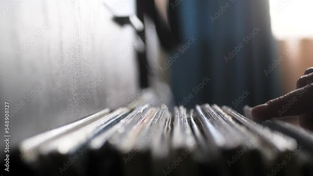 Male hands going through vinyl records, close up view. Audio music vintage records, browsing the records in LP collection. Slowmotion.