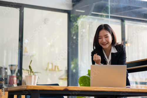 Canvas Print Happy Asian businesswoman working in cafe and using laptop computer and thinking