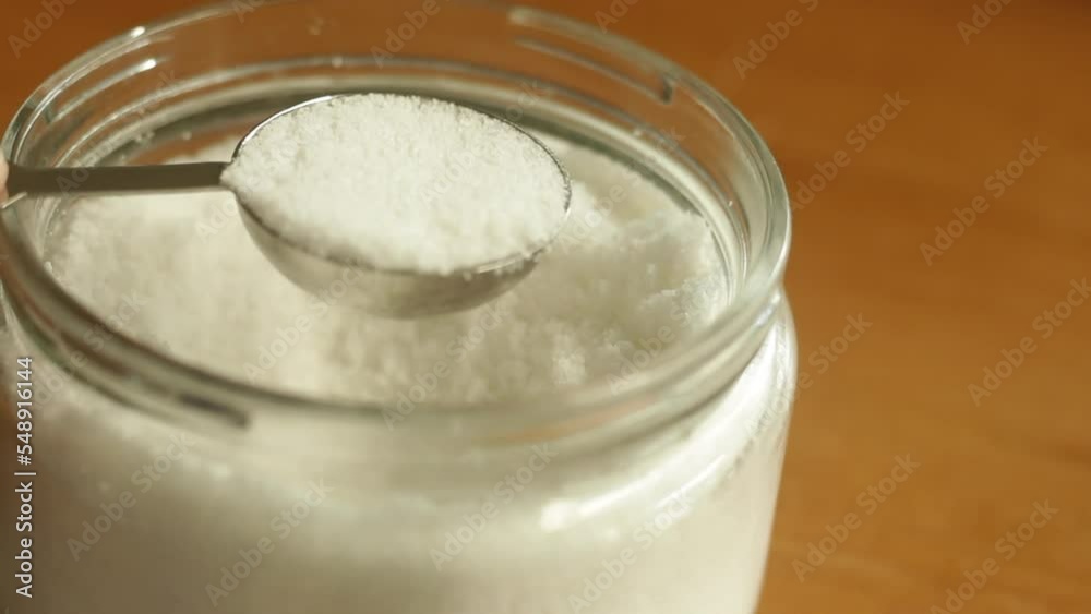 A tablespoon of table sea salt is being scooped with stainless steel measuring spoon cup A tablespoon of table sea salt is being scooped with stainless steel measuring spoon cup
