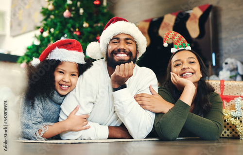 Christmas, portrait and family, kids and parents in lounge, winter celebration and love, care and happiness together. Happy family, girl and child celebrate festive holiday, santa hats or living room