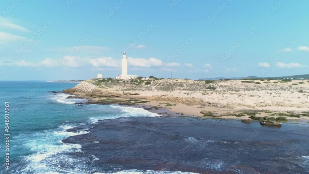 Aerial view from a drone of a lighthouse by the sea and the beach on a sunny day. Trafalgar Lighthouse, Cadiz, Spain Aerial view from a drone of a lighthouse by the sea and the beach on a sunny day. Trafalgar Lighthouse, Cadiz, Spain