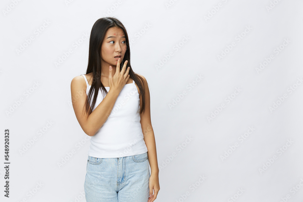 Asian woman hand signals, finger pointing facial skin problems, acne and inflammation, red rash and allergies, chicken pox, sadness from rashes. Facial skin care concept for diseases and nerves Asian woman hand signals, finger pointing facial skin problems, acne and inflammation, red rash and allergies, chicken pox, sadness from rashes. Facial skin care concept for diseases and nerves