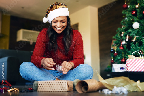 Woman, wrapping gift for Christmas with tape and gift box, holiday celebration and happiness. Happy woman on living room floor, present with ribbon and paper, smile and celebrate in family home.
