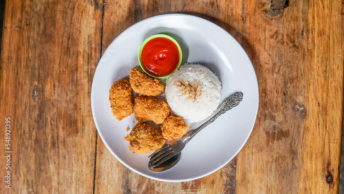 Chicken nuggets with sauce on a white plate on a wooden table. asian food