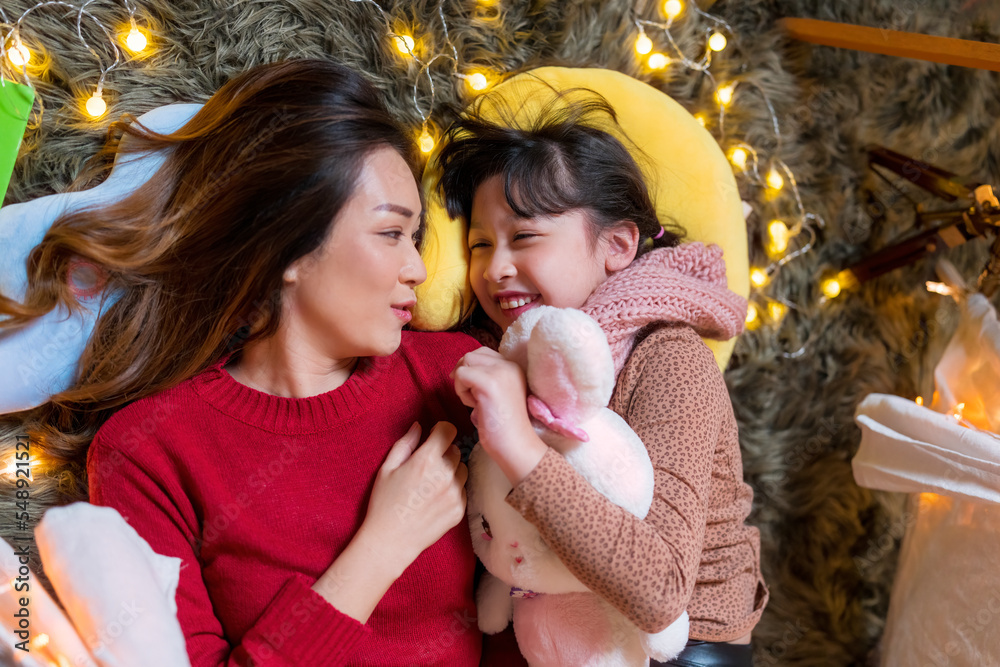 A Mother and her daughter having fun during Christmas time in bedroom decoration with Christmas light. A Mother and her daughter having fun during Christmas time in bedroom decoration with Christmas light.