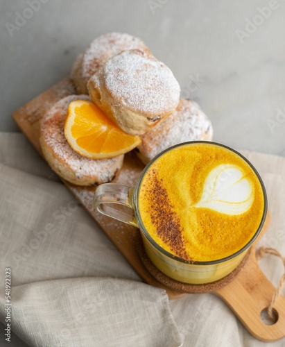 Closeup of baked British scones with turmeric latte on kitchen wooden board