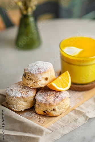 Closeup of baked British scones with turmeric latte on kitchen wooden board