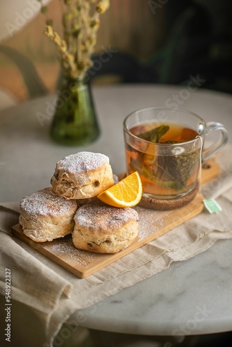 Closeup of baked British scones with tea on kitchen wooden board