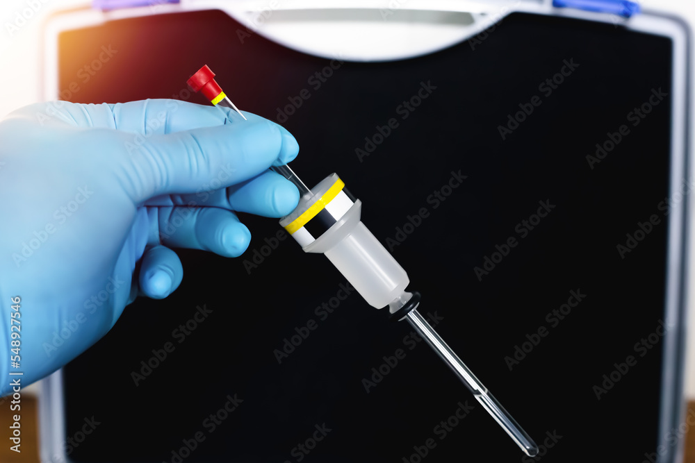 Hand of the scientist shows a sample solution in NMR tube with a