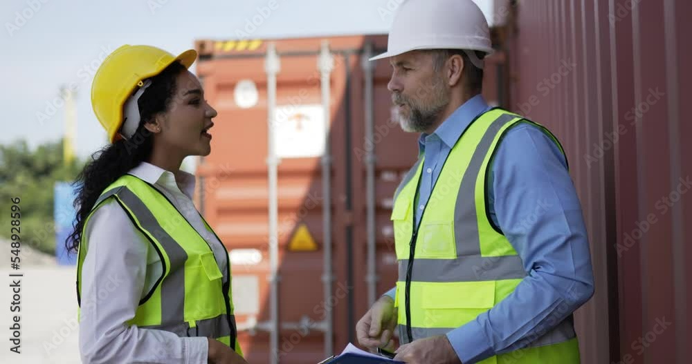 Handheld panning shot, middle-aged Caucasian business engineer man and pretty secretary female checking transport container, They are talking and hand shake together at storage port terminal Handheld panning shot, middle-aged Caucasian business engineer man and pretty secretary female checking transport container, They are talking and hand shake together at storage port terminal