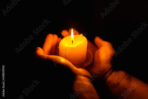 Burning candles in the boy hands on a dark background.Religious concept.